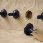 Piezas cerámicas azules en una pared y una pieza retirada con una etiqueta de papel