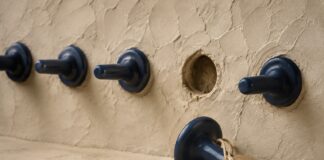 Piezas cerámicas azules en una pared y una pieza retirada con una etiqueta de papel
