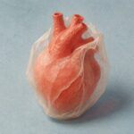 Corazón de papel rojo rodeado por una envoltura translúcida sobre fondo azul claro