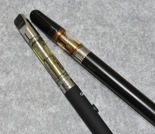 Vaporización de cannabis: ventajas e inconvenientes (I) Dos dispositivos de vapeo con depósitos transparentes sobre una superficie gris