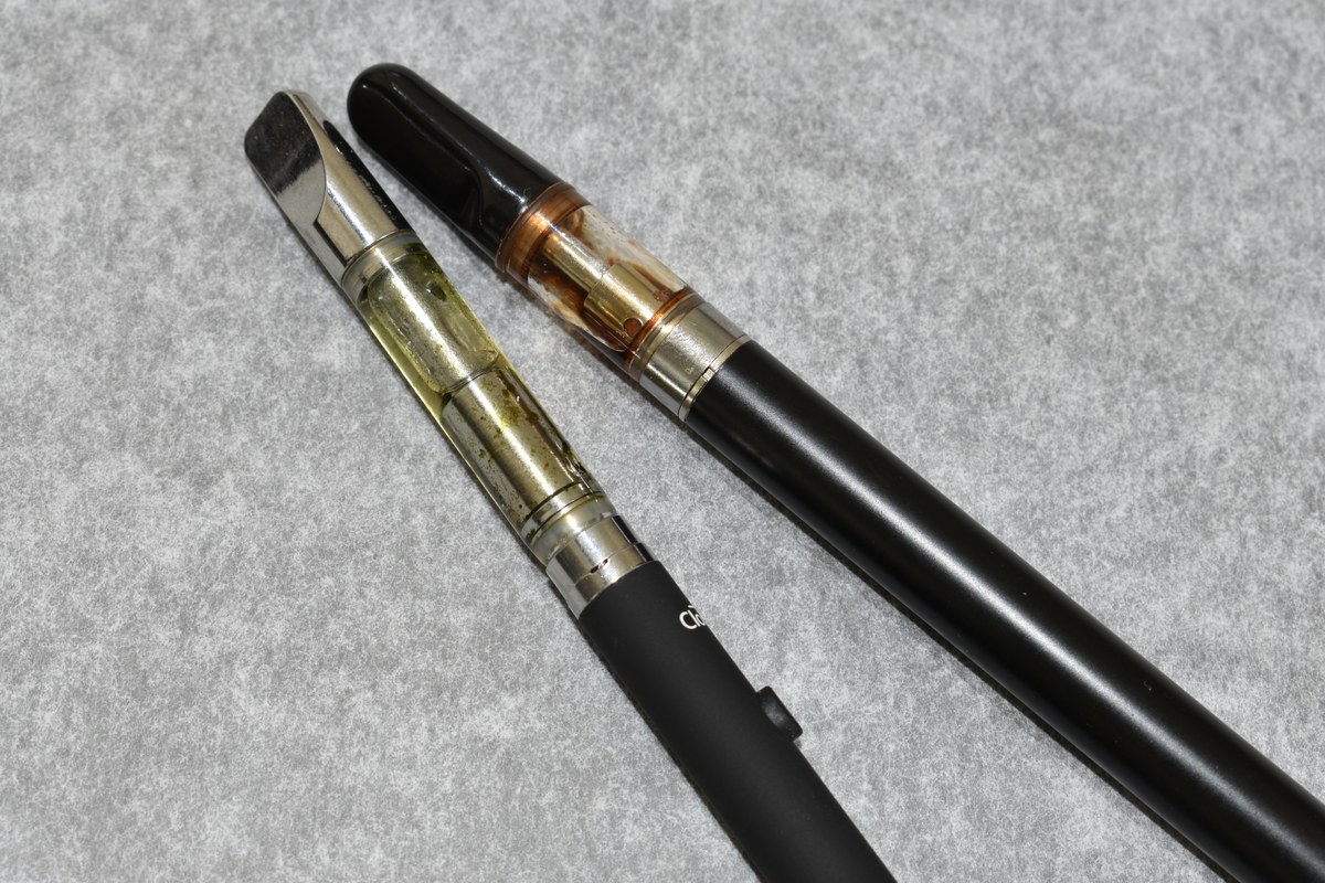 Dos dispositivos de vapeo con depósitos transparentes sobre una superficie gris