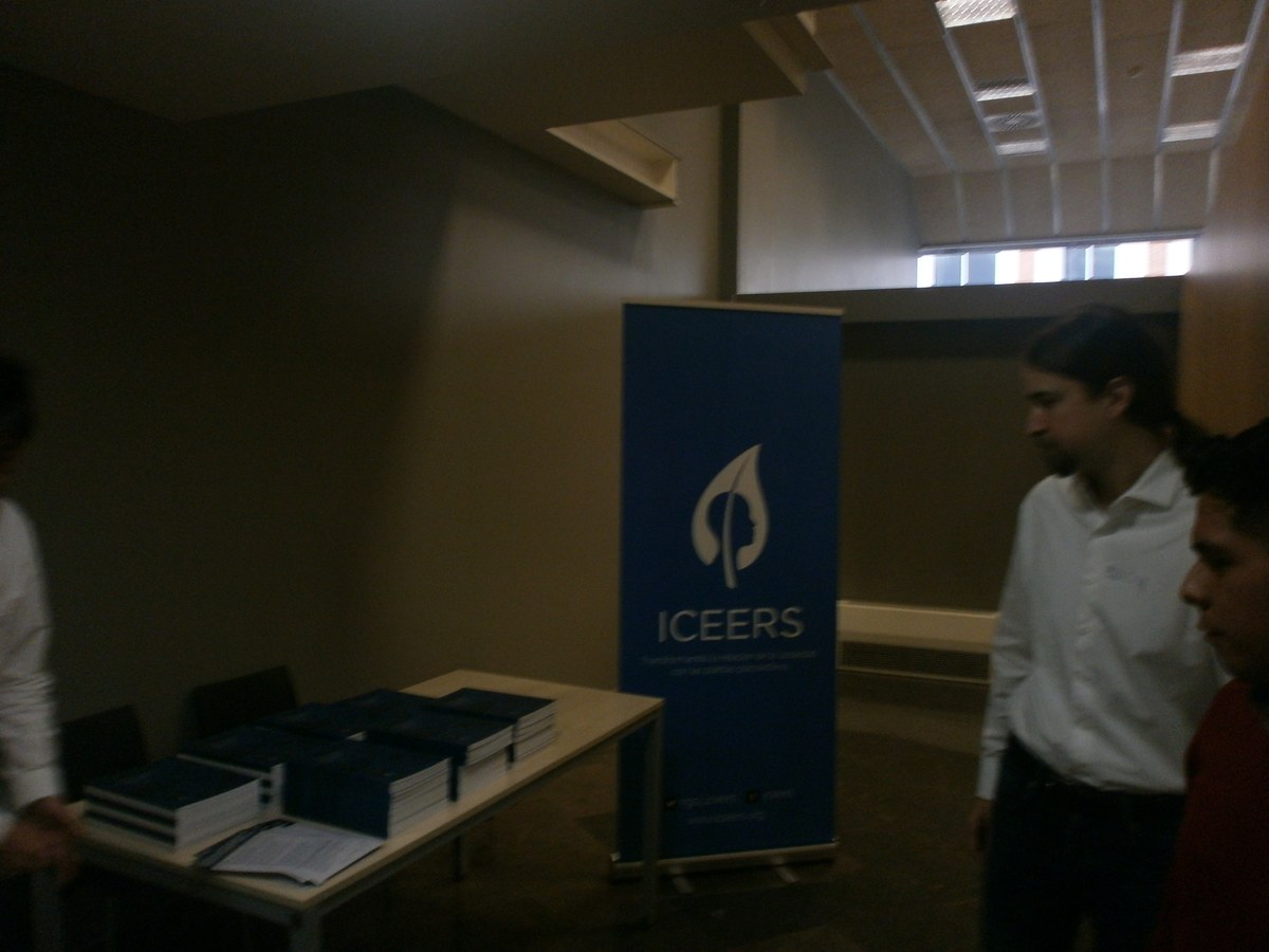 Dos hombres junto a una mesa con ejemplares del informe y un panel vertical de ICEERS.