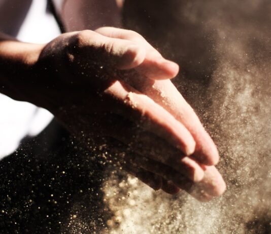 Cáñamo alimentario: cómo incorporarlo a la dieta Manos frotándose mientras desprenden una nube de polvo fino iluminada por el sol