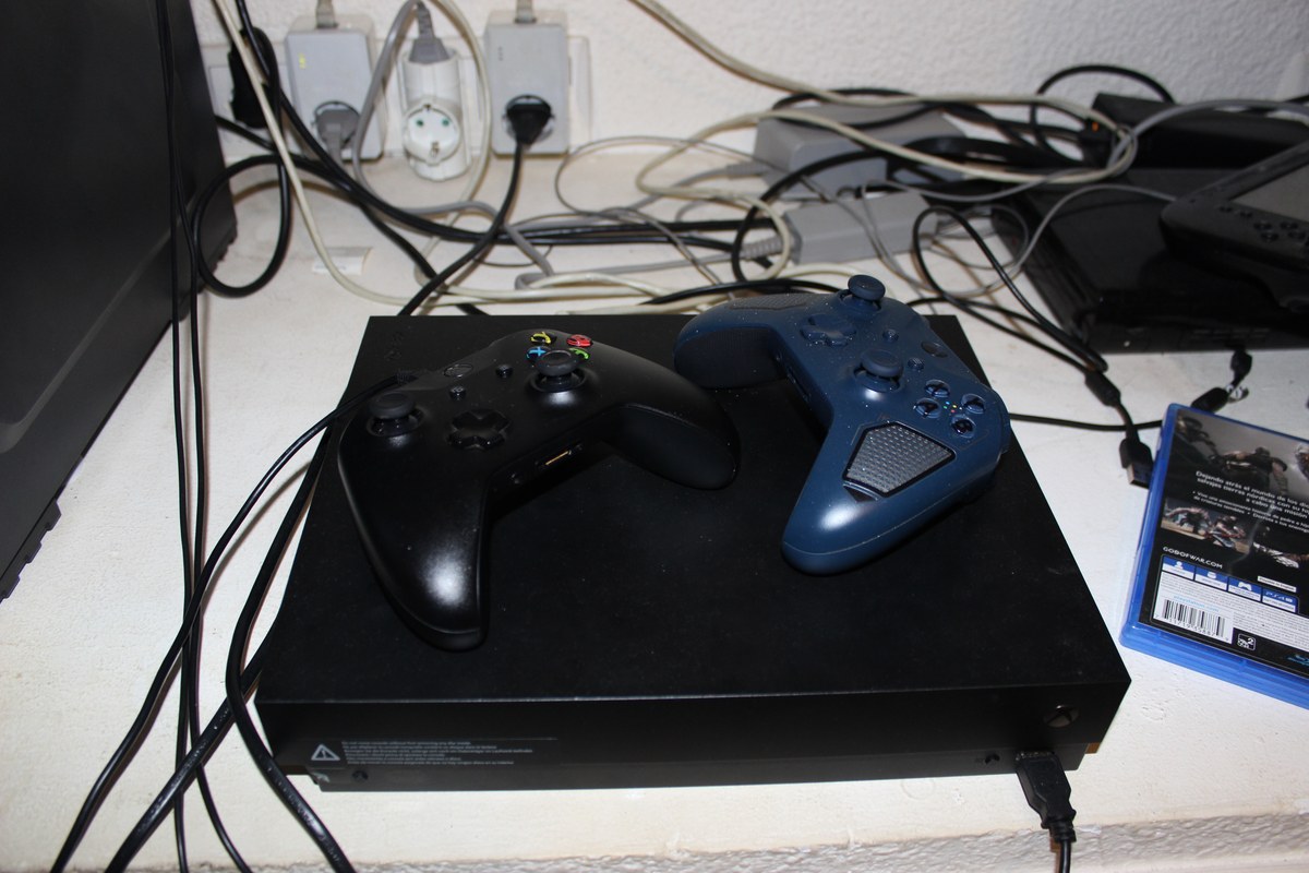 Dos mandos sobre una consola negra rodeada de cables y enchufes