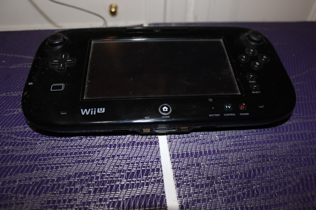 Mando Wii U negro con pantalla apagada sobre un mantel morado