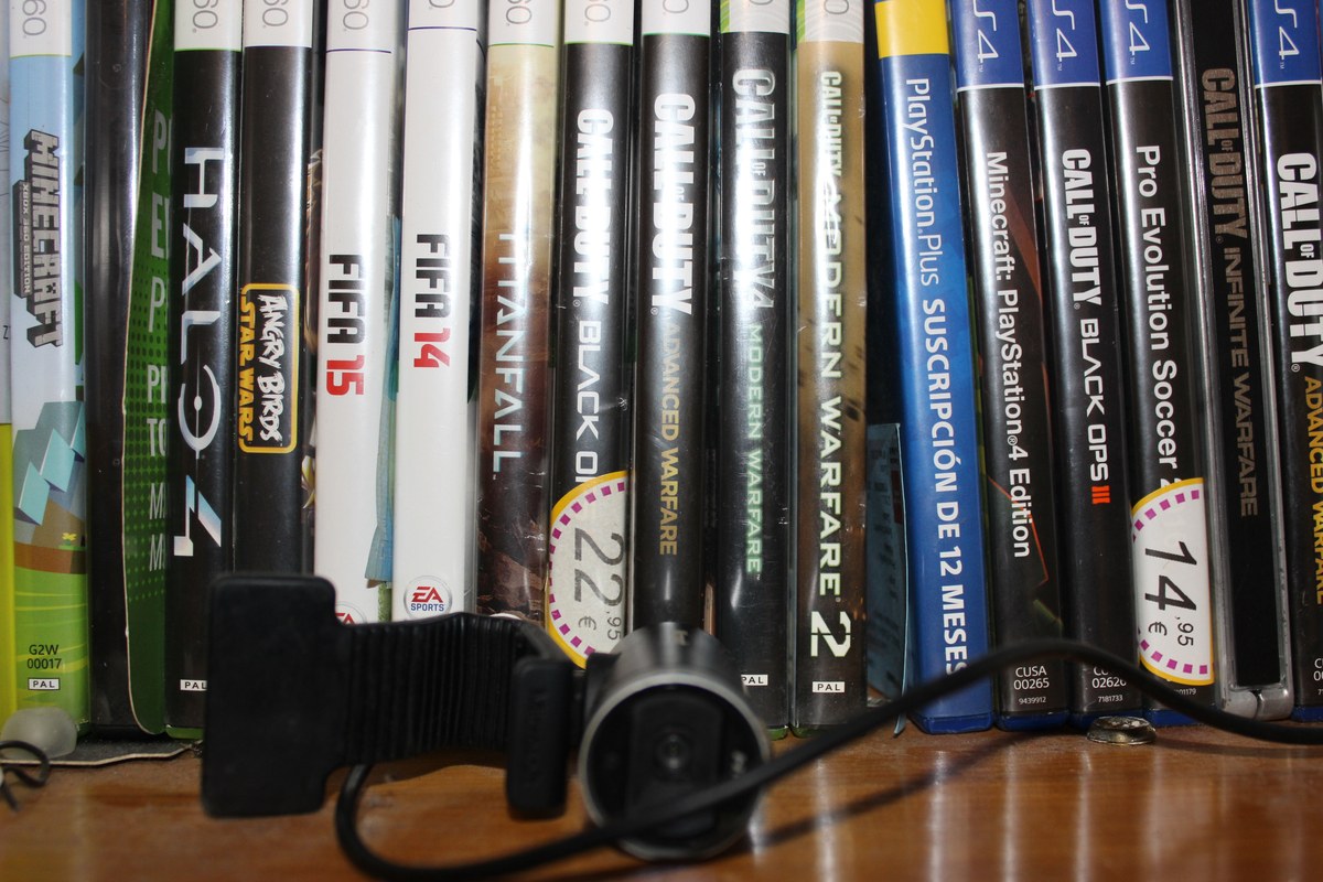 Estuche con videojuegos de consola, una cámara y accesorios sobre una mesa de madera