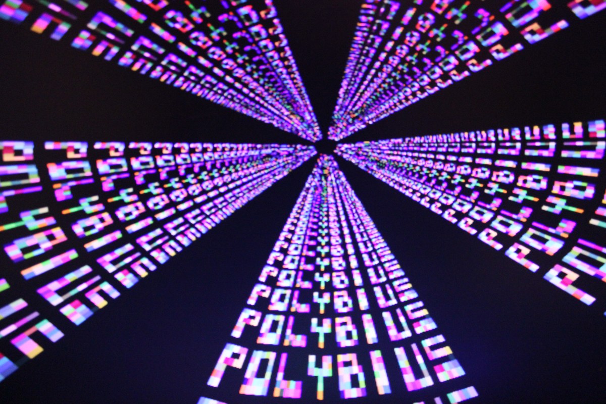 Filas de la palabra «PLAY» en tonos magenta, azul y blanco convergen hacia el centro sobre un fondo negro.