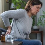Persona con dolor crónico de espalda junto a medicación analgésica y hojas de cannabis en segundo plano