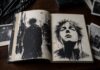 Los relatos de Xavi Cot, entre punk e ironía Libro de relatos abierto sobre una mesa junto a ilustraciones, fotografías y objetos de estética punk.