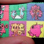 Peque&ntilde;o papel secante con cuadros de colores y personajes de dibujos animados, sostenido entre dos dedos