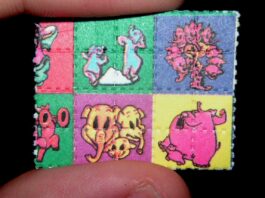 Cómo nació el mito de la droga caníbal Pequeño papel secante con cuadros de colores y personajes de dibujos animados, sostenido entre dos dedos