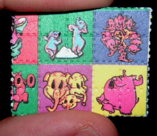 Cómo nació el mito de la droga caníbal Pequeño papel secante con cuadros de colores y personajes de dibujos animados, sostenido entre dos dedos