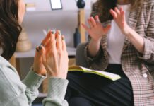 Psilocibina y sexo: un reanálisis en Reino Unido no aclara diferencias en depresión Plano de manos y cuadernos durante una conversación en una consulta, sin rostros visibles