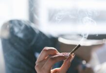Un estudio de EEUU vincula cannabis con peor sueño objetivo Una persona sostiene un porro encendido mientras permanece tumbada en una cama