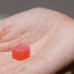 Una peque&ntilde;a gominola roja azucarada sobre la palma de una mano