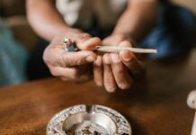Un ensayo de EE UU relaciona el efecto del cannabis con el sexo y la frecuencia de uso Unas manos sostienen un porro sobre un cenicero situado en una mesa de madera