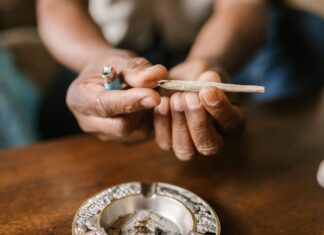 Un ensayo de EE UU relaciona el efecto del cannabis con el sexo y la frecuencia de uso Unas manos sostienen un porro sobre un cenicero situado en una mesa de madera