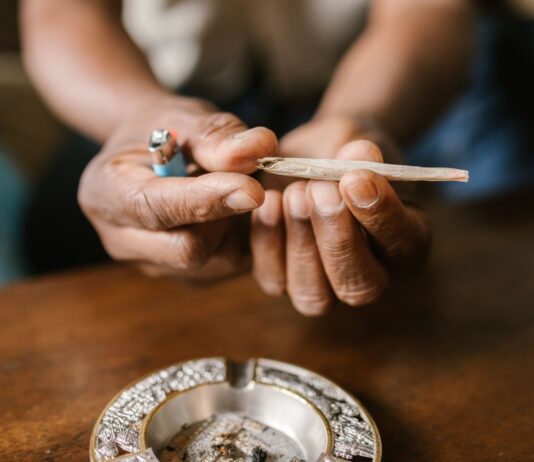 Un ensayo de EE UU relaciona el efecto del cannabis con el sexo y la frecuencia de uso Unas manos sostienen un porro sobre un cenicero situado en una mesa de madera