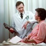 M&eacute;dico de oncolog&iacute;a consulta con una paciente en una habitaci&oacute;n hospitalaria