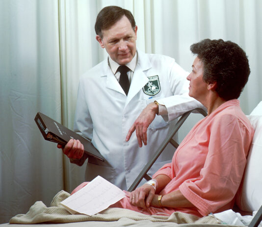 M&eacute;dico de oncolog&iacute;a consulta con una paciente en una habitaci&oacute;n hospitalaria