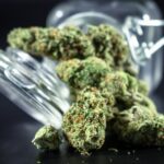 Flores secas de cannabis junto a un tarro de cristal