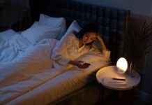 Cannabis e insomnio en Reino Unido: un registro observa mejoras a dos años Una mujer mira el móvil en la cama, con la habitación iluminada por una lámpara