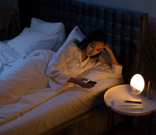 Cannabis e insomnio en Reino Unido: un registro observa mejoras a dos años Una mujer mira el móvil en la cama, con la habitación iluminada por una lámpara